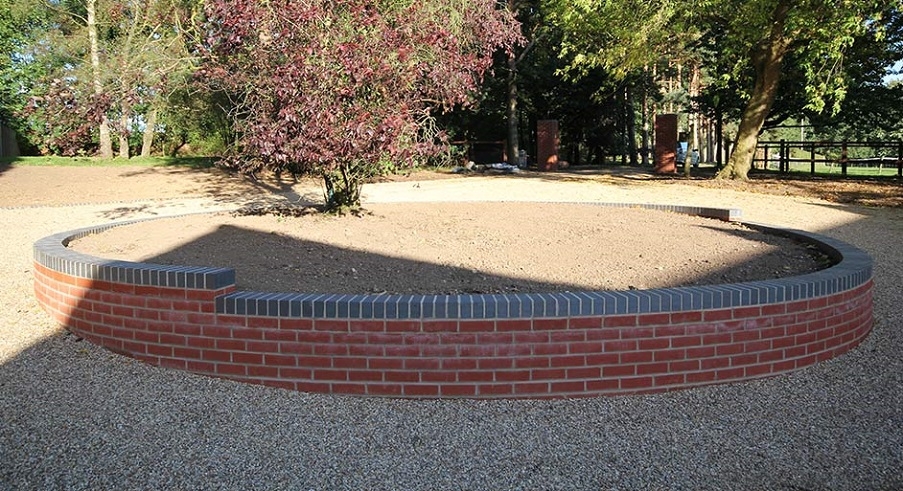 A brick wall surrounding a tree by Knights Paving & Landscaping