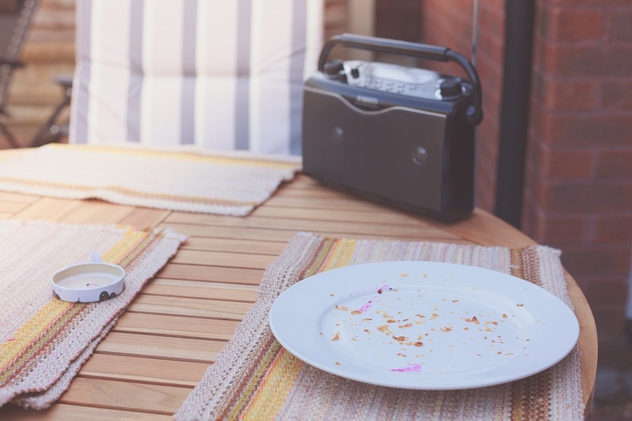 A radio on a garden table, with plates with crumbs on