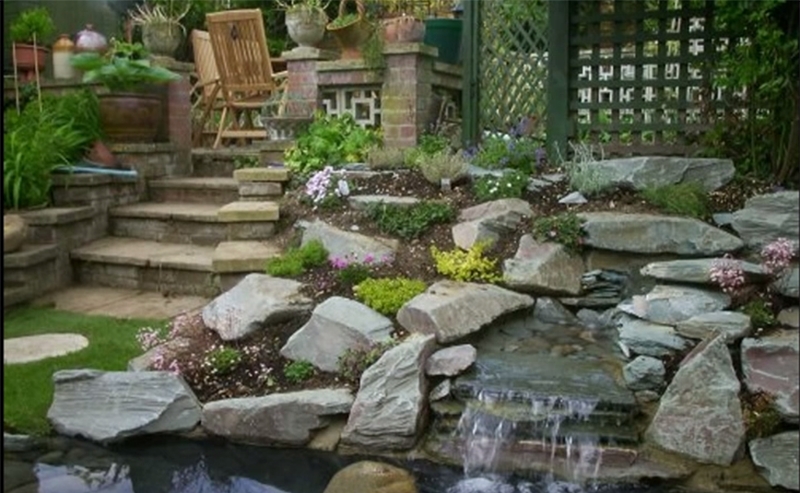 A pond with a waterfall feature surrounded by a rockery.